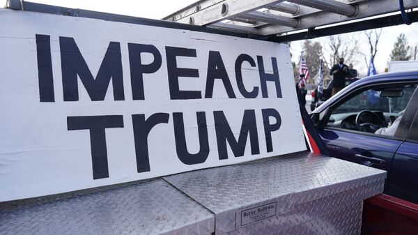 A sign stands in the box of a pickup truck during a gathering calling for the impeachment of President Donald Trump at South High School before a car rally through the streets of downtown Sunday, 10 January 2021, in Denver.  - Sputnik International