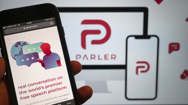 The website of the social media platform Parler is displayed in Berlin, Jan. 10, 2021. The platform's logo is on a screen in the background. The conservative-friendly social network Parler was booted off the internet Monday, Jan. 11, over ties to last week's siege on the U.S. Capitol, but not before hackers made off with an archive of its posts, including any that might have helped organize or document the riot.  - Sputnik International