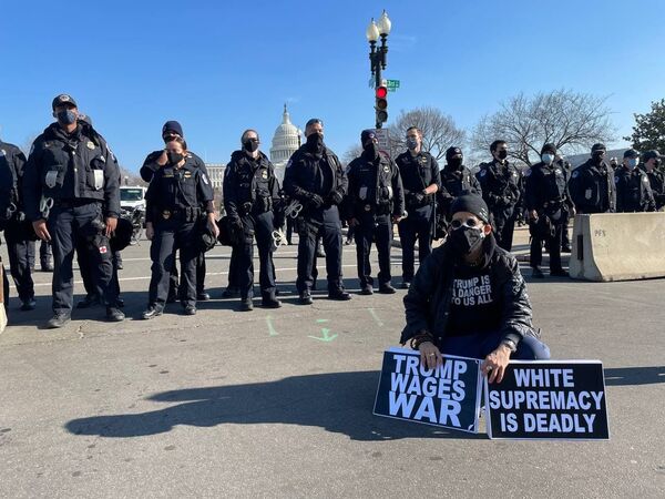 Am anti-Trump protester and police officers outside the US Capitol as the House of Representatives votes to impeach Trump.  - Sputnik International