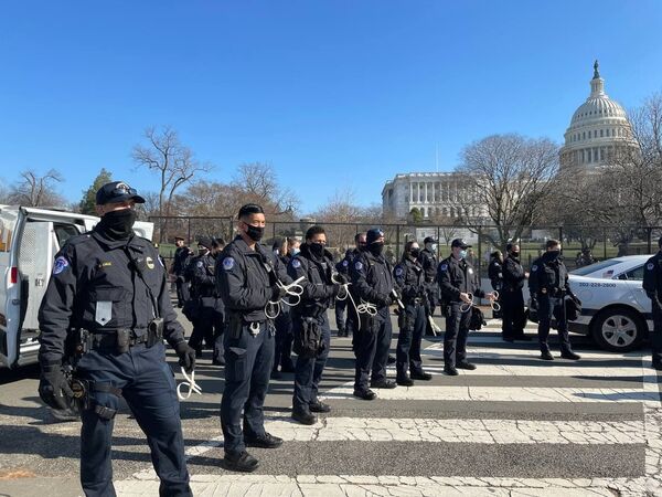 Police officers stand guard outside the US Capitol building as the House of Representatives votes to impeach Trump.  - Sputnik International