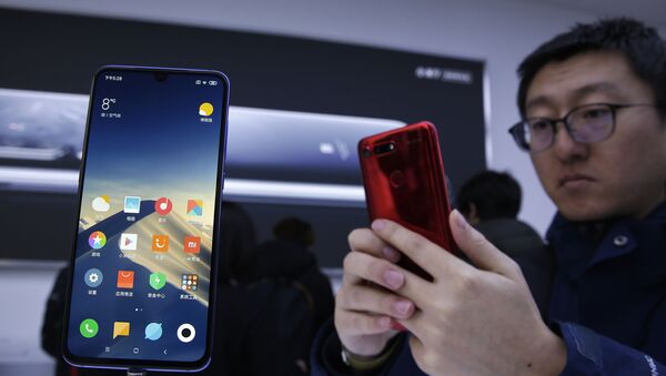 An invited guest takes a photo of Xiaomi new model Mi 9 displayed on an exhibition booth after its launch event in Beijing, Wednesday, 20 February 2019 - Sputnik International