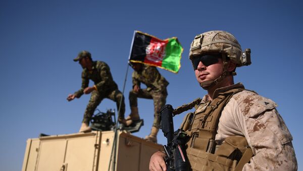 In this photograph taken on August 28, 2017, a US Marine looks on as Afghan National Army soldiers raise the Afghan National flag on an armed vehicle during a training exercise to deal with IEDs (improvised explosive devices) at the Shorab Military Camp in Lashkar Gah in Helmand province. - Marines in Afghanistan's Helmand say Donald Trump's decision to keep boots on the ground indefinitely gives them all the time in the world to retake the province, once the symbol of US intervention but now a Taliban stronghold. They may need it. At the hot, dusty Camp Shorab, where many of the recently deployed Marines train their Afghan counterparts in flat, desert terrain, the Afghans admit th - Sputnik International