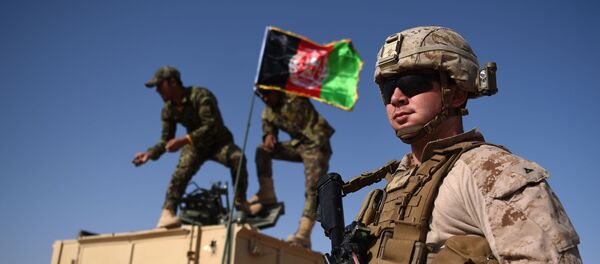 In this photograph taken on August 28, 2017, a US Marine looks on as Afghan National Army soldiers raise the Afghan National flag on an armed vehicle during a training exercise to deal with IEDs (improvised explosive devices) at the Shorab Military Camp in Lashkar Gah in Helmand province. - Marines in Afghanistan's Helmand say Donald Trump's decision to keep boots on the ground indefinitely gives them all the time in the world to retake the province, once the symbol of US intervention but now a Taliban stronghold. They may need it. At the hot, dusty Camp Shorab, where many of the recently deployed Marines train their Afghan counterparts in flat, desert terrain, the Afghans admit th - Sputnik International