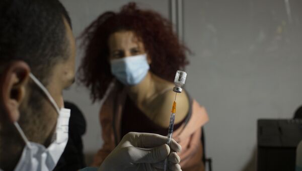 A medical professional prepares to administer the Pfizer COVID-19 vaccine to a woman at a makeshift vaccination center in a sports arena in Jerusalem, Thursday, Jan. 14, 2021. - Sputnik International