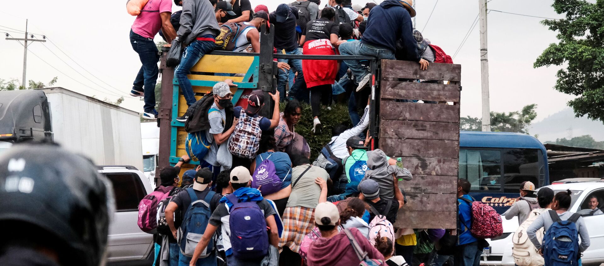 Hondurans climb onto the back of a truck for a ride in a new caravan of migrants, set to head to the United States, in Cofradia, Honduras January 15, 2021. - Sputnik International, 1920, 18.01.2021