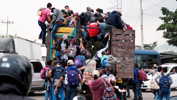 Hondurans climb onto the back of a truck for a ride in a new caravan of migrants, set to head to the United States, in Cofradia, Honduras January 15, 2021. - Sputnik International