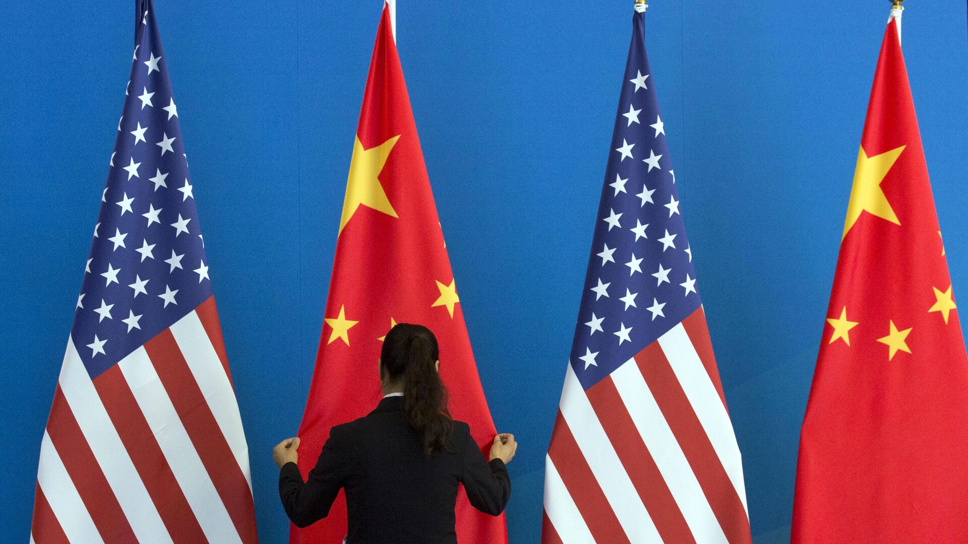 A Chinese woman adjusts the Chinese national flag near U.S. national flags before a Strategic Dialogue expanded meeting that's part of the U.S.-China Strategic and Economic Dialogue at the Diaoyutai State Guesthouse in Beijing, Thursday, July 10, 2014 - Sputnik International, 1920, 16.11.2023