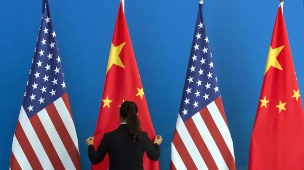 A Chinese woman adjusts the Chinese national flag near U.S. national flags before a Strategic Dialogue expanded meeting that's part of the U.S.-China Strategic and Economic Dialogue at the Diaoyutai State Guesthouse in Beijing, Thursday, July 10, 2014 - Sputnik International