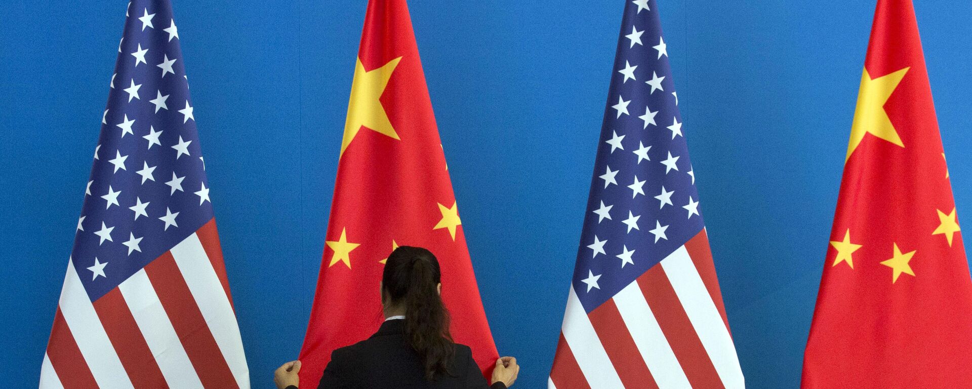 A Chinese woman adjusts the Chinese national flag near U.S. national flags before a Strategic Dialogue expanded meeting that's part of the U.S.-China Strategic and Economic Dialogue at the Diaoyutai State Guesthouse in Beijing, Thursday, July 10, 2014 - Sputnik International, 1920, 02.08.2022