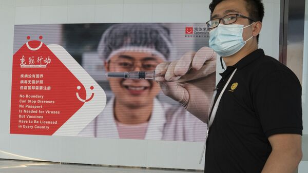 An employee of SinoVac stands near an advertisement for its SARS CoV-2 Vaccine for COVID-19 named CoronaVac at its factory in Beijing on Thursday, Sept. 24, 2020 - Sputnik International