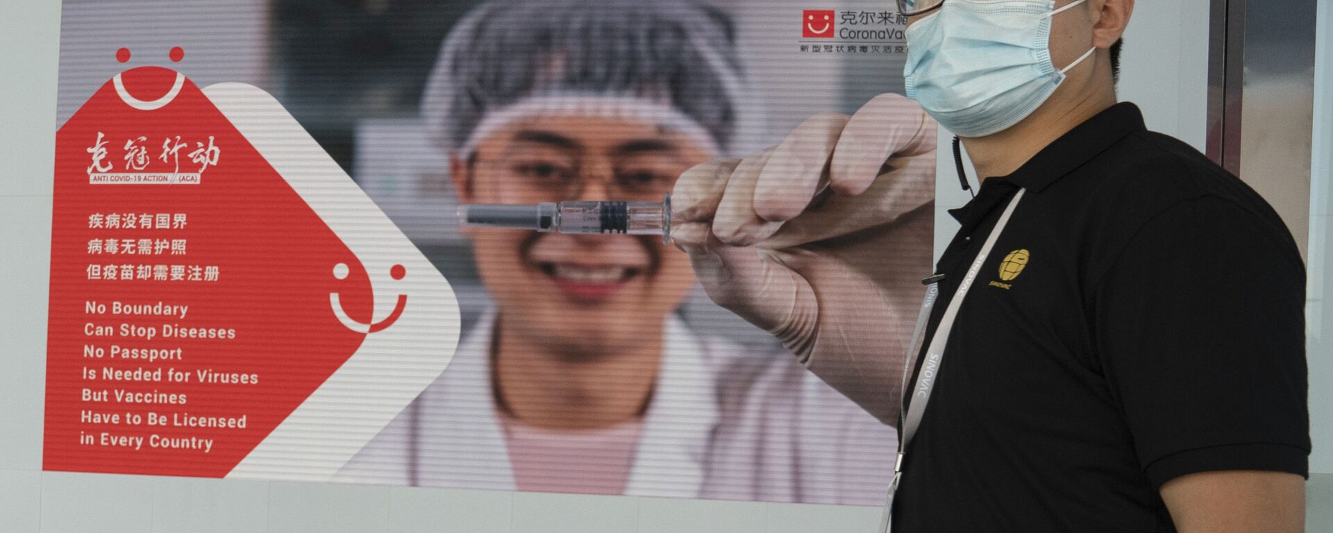 An employee of SinoVac stands near an advertisement for its SARS CoV-2 Vaccine for COVID-19 named CoronaVac at its factory in Beijing on Thursday, Sept. 24, 2020 - Sputnik International, 1920