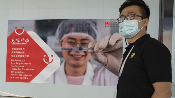An employee of SinoVac stands near an advertisement for its SARS CoV-2 Vaccine for COVID-19 named CoronaVac at its factory in Beijing on Thursday, Sept. 24, 2020 - Sputnik International