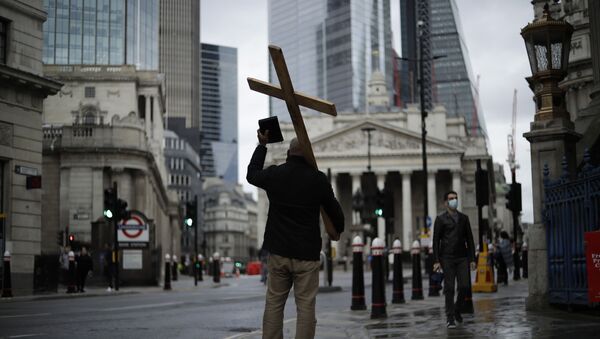 A man holding a cross and a Bible preaches about Christianity backdropped by the Royal Exchange, back center, and the Bank of England, at left, during England's second coronavirus lockdown in the City of London financial district of London, Wednesday, Nov. 18, 2020 - Sputnik International