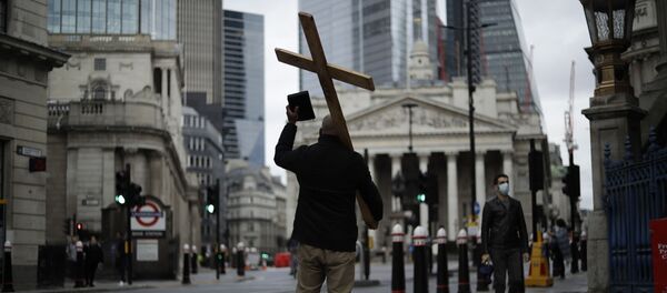 A man holding a cross and a Bible preaches about Christianity backdropped by the Royal Exchange, back center, and the Bank of England, at left, during England's second coronavirus lockdown in the City of London financial district of London, Wednesday, Nov. 18, 2020 - Sputnik International