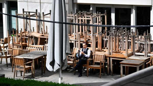 A person sits on a chair outside a closed pub in Canary Wharf, following the outbreak of the coronavirus disease (COVID-19), London, Britain, May 27, 2020 - Sputnik International