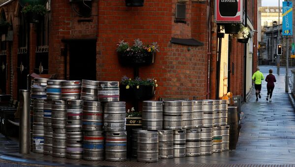 People run past a pile of empty beer barrels outside a closed pub amid the COVID-19 pandemic in Belfast, Northern Ireland January 2, 2021 - Sputnik International