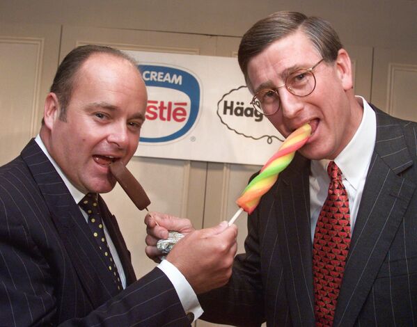 Paul Walsh, left, chairman and CEO of Pillsbury, gets a bite of a Haagen-Dazs ice cream bar from Joe Weller, chairman and CEO of Nestle USA, who samples an Itzakadoozie frozen pop after a New York news conference, 19 Aug, 1999.  - Sputnik International