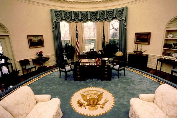 This 22 January 1990 file photo released by the White House shows President George HW Bush's Oval Office at the White House in Washington. Bush's redecoration of the Oval Office included a new rug with a gold Presidential Seal, new draperies, a coffee table, and two tall armchairs. Presidents typically put their own touches on the Oval Office early in their terms.   - Sputnik International