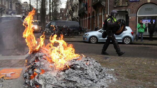 A police officer walks near a fire during a protest against restrictions put in place to curb the spread of the coronavirus disease (COVID-19), in Amsterdam, Netherlands January 24, 2021 - Sputnik International