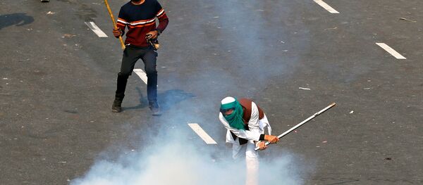 A demonstrator uses a stick to hit a tear gas canister during a protest against farm laws introduced by the government, in New Delhi, India, January 26, 2021 - Sputnik International