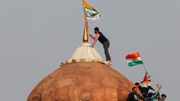 A farmer puts a flag on top of the historic Red Fort, during a protest against farm laws introduced by the government, in Delhi, India, January 26, 2021 - Sputnik International