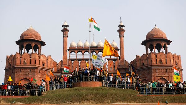 Farmers wave flags during a protest against farm laws introduced by the government, at the historic Red Fort in Delhi, India, January 26, 2021 - Sputnik International