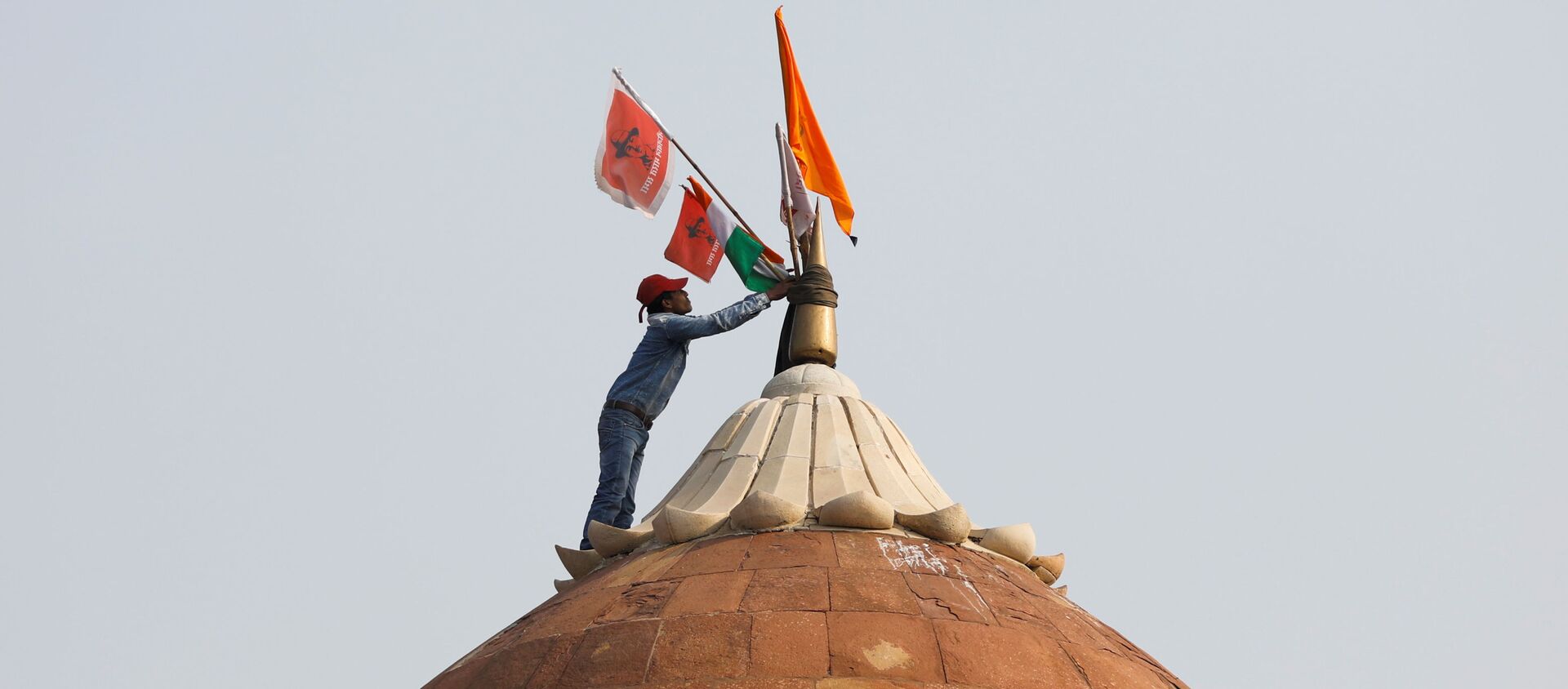 A man holds a flag as he stands on the top of the historic Red Fort during a protest against farm laws introduced by the government, in Delhi - Sputnik International, 1920, 31.01.2021