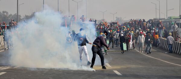 A man throws a tear gas canister back at police during a tractor rally held by farmers to protest farm laws on the occasion of India's Republic Day at Ghazipur border near Delhi - Sputnik International