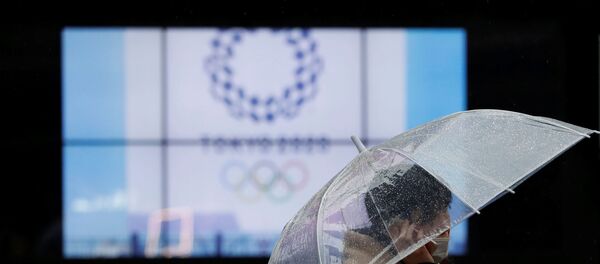 A passerby wearing a protective face mask walks past a display showing the logo of Tokyo 2020 Olympic Games that have been postponed to 2021 due to the coronavirus disease (COVID-19) outbreak, in Tokyo, Japan January 23, 2021. - Sputnik International
