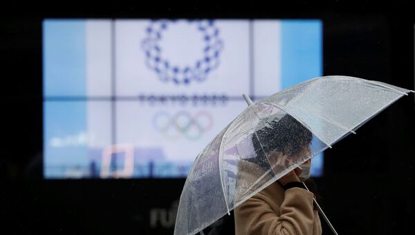 A passerby wearing a protective face mask walks past a display showing the logo of Tokyo 2020 Olympic Games that have been postponed to 2021 due to the coronavirus disease (COVID-19) outbreak, in Tokyo, Japan January 23, 2021. - Sputnik International