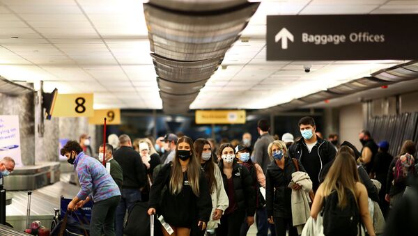Travelers wearing protective face masks to prevent the spread of the coronavirus disease (COVID-19) reclaim their luggage at the airport in Denver, Colorado, U.S., November 24, 2020.   - Sputnik International
