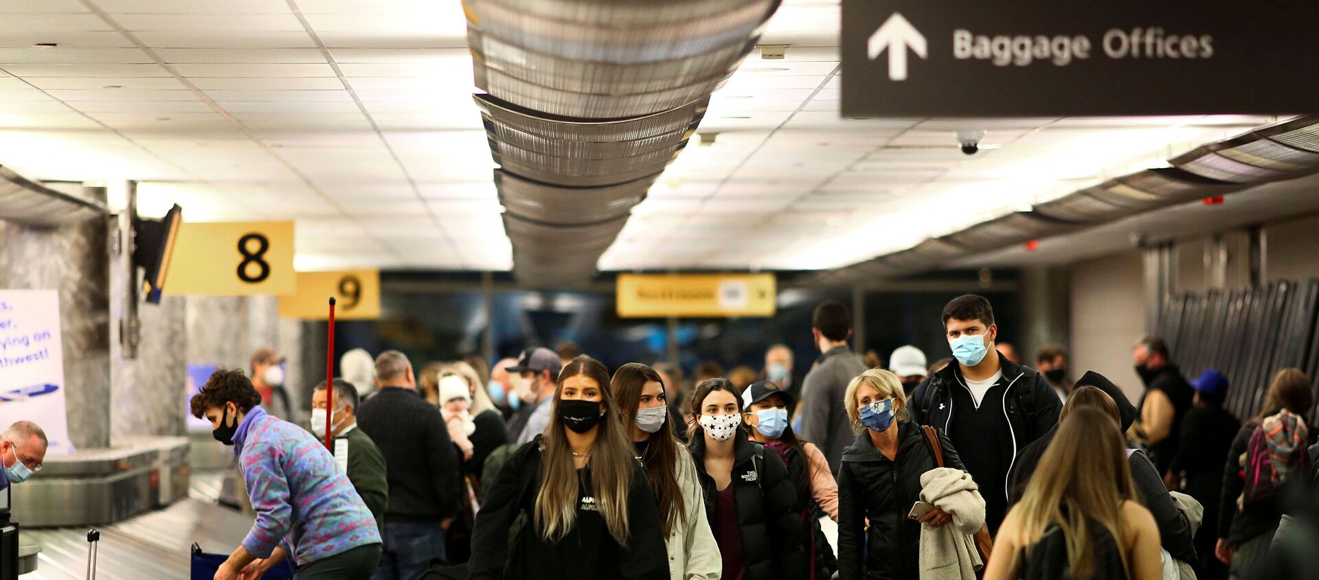 Travelers wearing protective face masks to prevent the spread of the coronavirus disease (COVID-19) reclaim their luggage at the airport in Denver, Colorado, U.S., November 24, 2020.   - Sputnik International, 1920, 20.02.2021