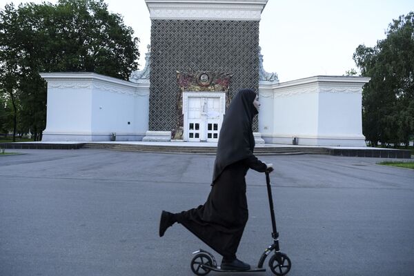 A woman wearing a hijab rides a scooter in Moscow on 14 June 2020. - Sputnik International