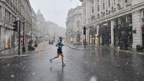 A jogger taking his daily exercise, crosses Regent Street in London in the snow on January 24, 2021, as the capital experiences a rare covering of snow on Sunday. - Sputnik International