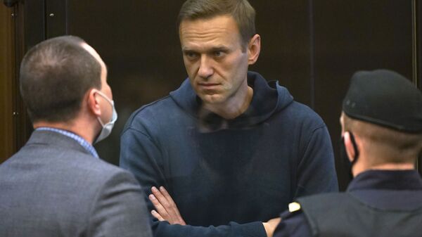 In this handout photo provided by Moscow City Court Russian opposition leader Alexei Navalny talks to one of his lawyers, left, while standing in the cage during a hearing to a motion from the Russian prison service to convert the suspended sentence of Navalny from the 2014 criminal conviction into a real prison term in the Moscow City Court in Moscow, Russia, Tuesday, Feb. 2, 2021. - Sputnik International