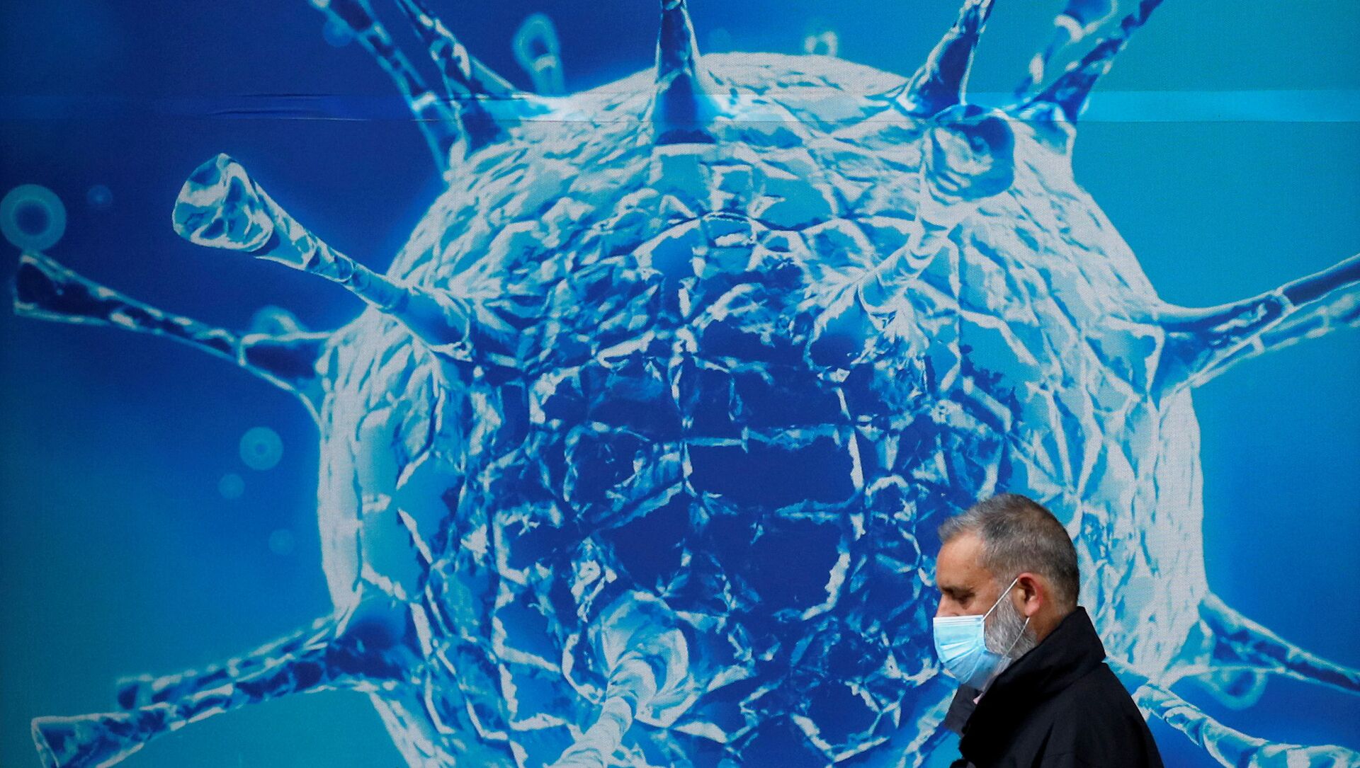 FILE PHOTO: A man wearing a protective face mask walks past an illustration of a virus outside a regional science centre amid the coronavirus disease (COVID-19) outbreak, in Oldham, Britain 3 August 2020. - Sputnik International, 1920, 11.02.2021