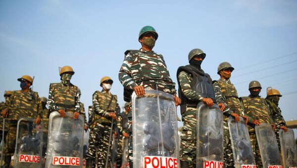 Police officers in riot gear stand guard at the site of a protest against the farm laws at Singhu border in New Delhi - Sputnik International