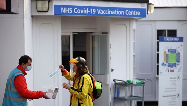 A woman is given a protective face mask as she waits to receive the COVID-19 vaccine at Crystal Palace Football Club Vaccination Centre, amid the outbreak of the coronavirus disease (COVID-19) in London, Britain February 4, 2021.  - Sputnik International