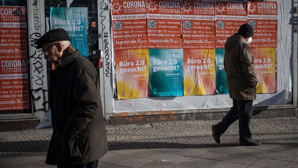 People walk past a closed shop front with posters advertising a Corona test centre in Berlin's Kreuzberg district on February 1, 2021 amid the ongoing coronavirus COVID-19 pandemic. - Sputnik International