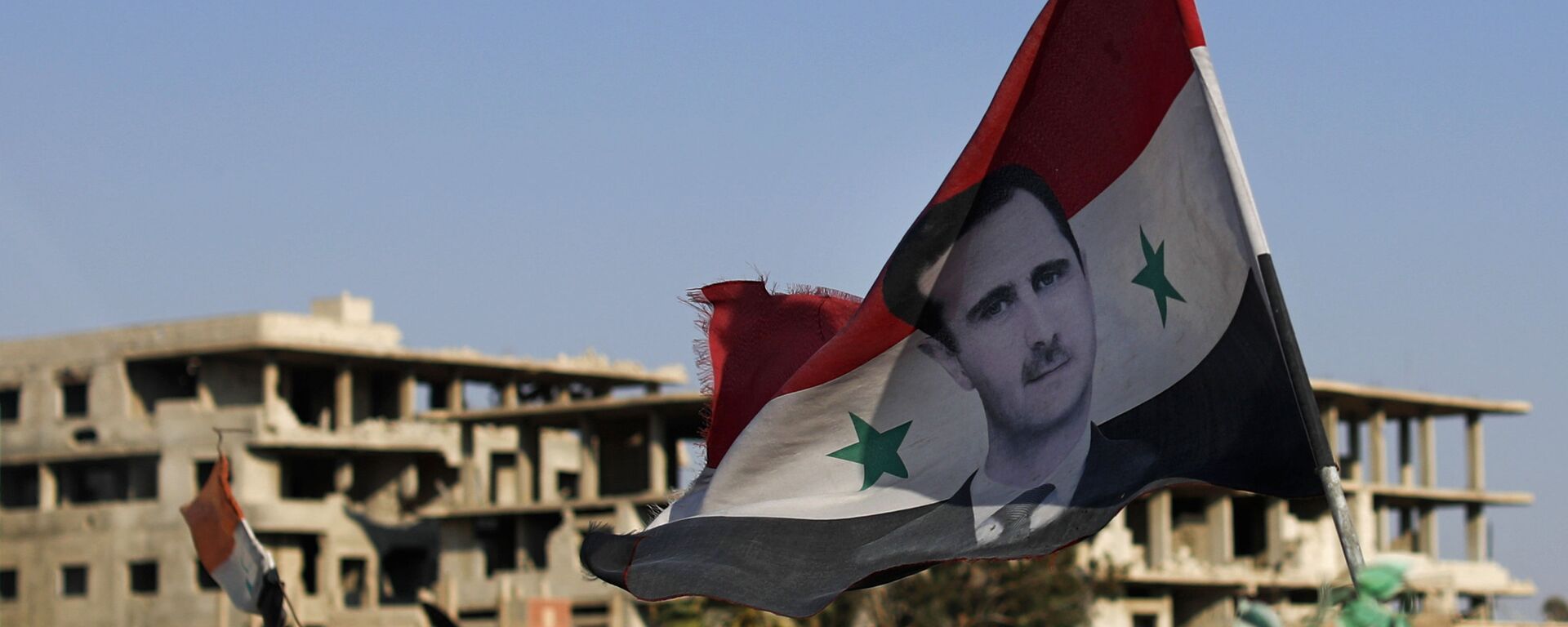 In this July 15, 2018 file photo, a Syrian national flag with a picture of Syrian President Bashar Assad flies at an Army check point, in the town of Douma in the eastern Ghouta region, near Damascus, Syria. - Sputnik International, 1920, 02.10.2023