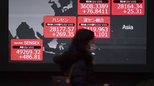 A woman wearing a face mask to help curb the spread of the coronavirus walks past an electronic stock board showing Japan's Nikkei 225 and other Asian indexes at a securities firm in Tokyo Tuesday, Jan. 12, 2021. - Sputnik International