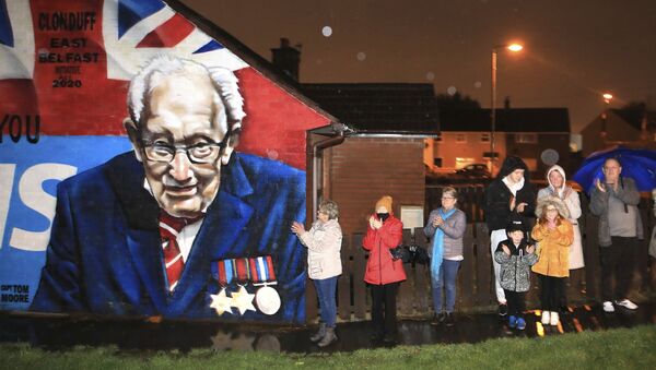 Local residents join a national clap beside a mural of Captain Sir Tom Moore in East Belfast, Northern Ireland, Wednesday, Feb. 3, 2021. Captain Moore passed away Tuesday after being treated with Covid-19 and was known for his achievements raising millions of pounds for the NHS charity during the Covid-19 pandemic.  - Sputnik International