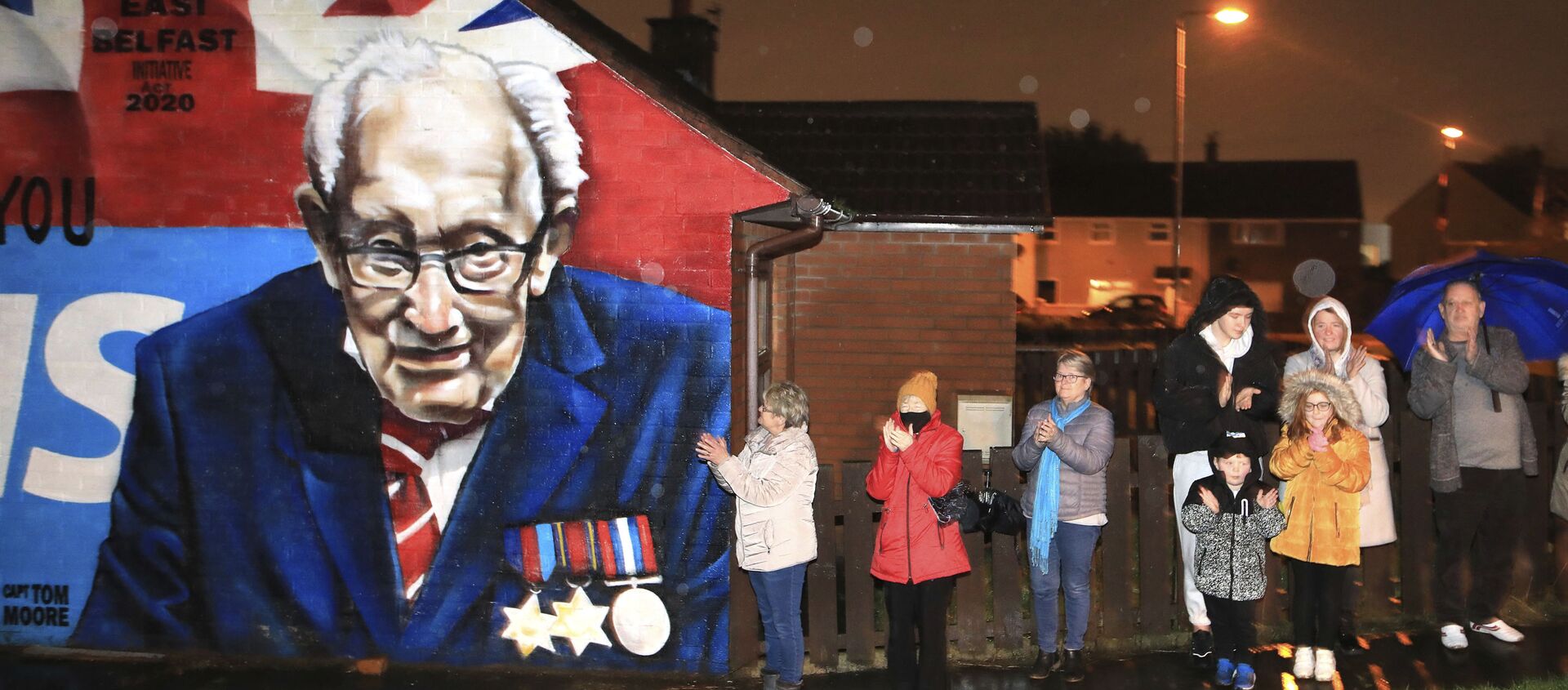 Local residents join a national clap beside a mural of Captain Sir Tom Moore in East Belfast, Northern Ireland, Wednesday, Feb. 3, 2021. Captain Moore passed away Tuesday after being treated with Covid-19 and was known for his achievements raising millions of pounds for the NHS charity during the Covid-19 pandemic.  - Sputnik International, 1920, 08.02.2021