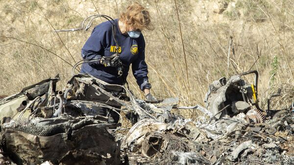 FILE - In this Jan. 27, 2020, file photo, released by the National Transportation Safety Board, NTSB investigator Carol Hogan examines wreckage as part of the NTSB's investigation of a helicopter crash near Calabasas, Calif., that killed former NBA basketball player Kobe Bryant, his 13-year-old daughter, Gianna, and seven others. Federal safety investigators bypassed aviation regulators on Tuesday, June 2, 2020, and urged leading helicopter manufacturers to install so-called black boxes that would help determine the cause of crashes such as the one that killed former NBA star Kobe Bryant. - Sputnik International