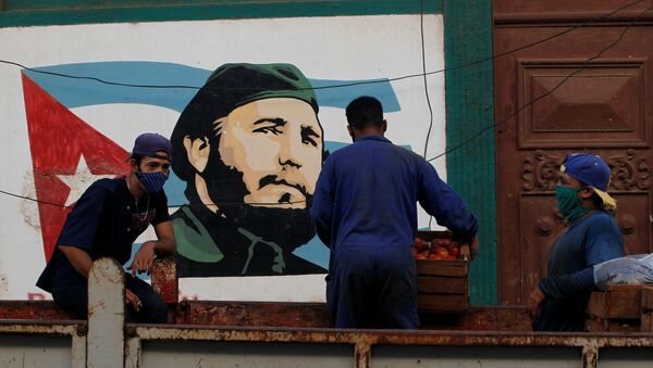 Workers stand on the back of a truck next to an image of late Cuban leader Fidel Castro, in Havana - Sputnik International