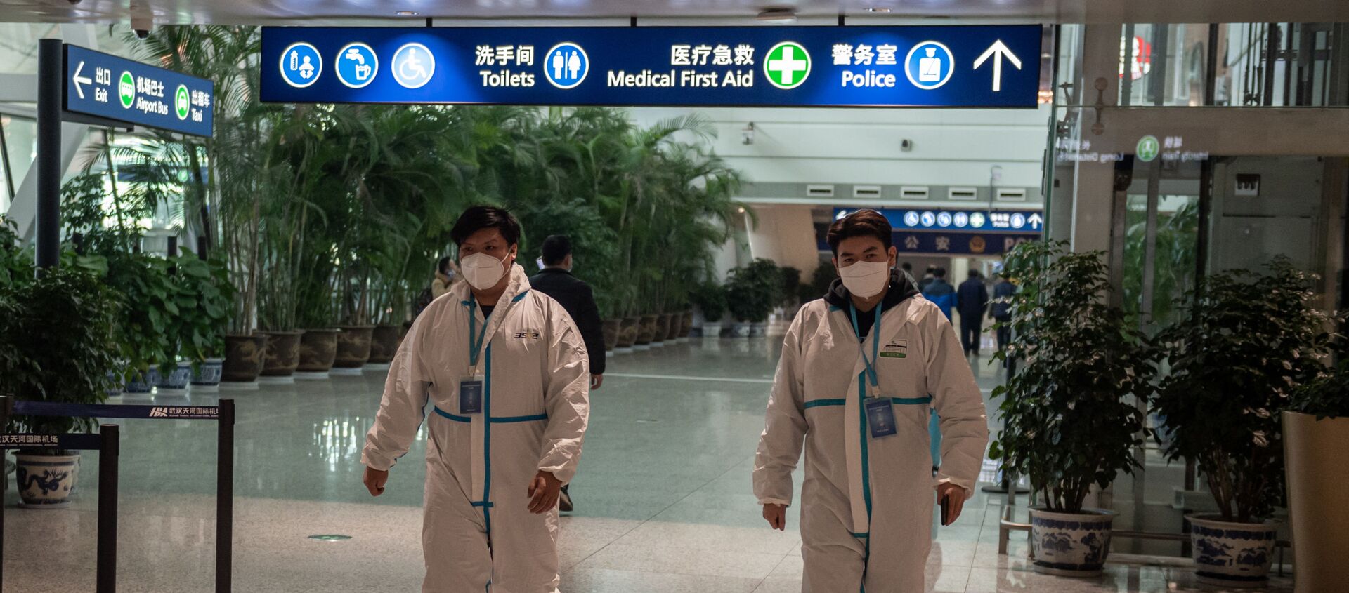 Health workers in suits walk in the international arrivals area, where arriving travelers are to be taken into quarantine, at the international airport in Wuhan on January 14, 2021, ahead of the expected arrival of a World Health Organization (WHO) team investigating the origins of the Covid-19 pandemic. (Photo by NICOLAS ASFOURI / AFP) - Sputnik International, 1920, 14.02.2021