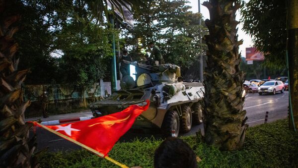 A man waves a flag next to an armoured vehicle during a protest against the military coup, in Yangon, Myanmar, 14 February 2021.  - Sputnik International