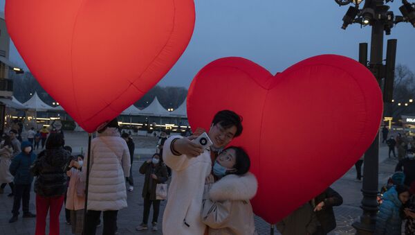 A couple takes a selfie amongst lit heart shaped balloons on Chinese Valentine's Day which coincides with the third day of the Chinese Lunar New Year in Beijing on Sunday, Feb. 14, 2021.  - Sputnik International