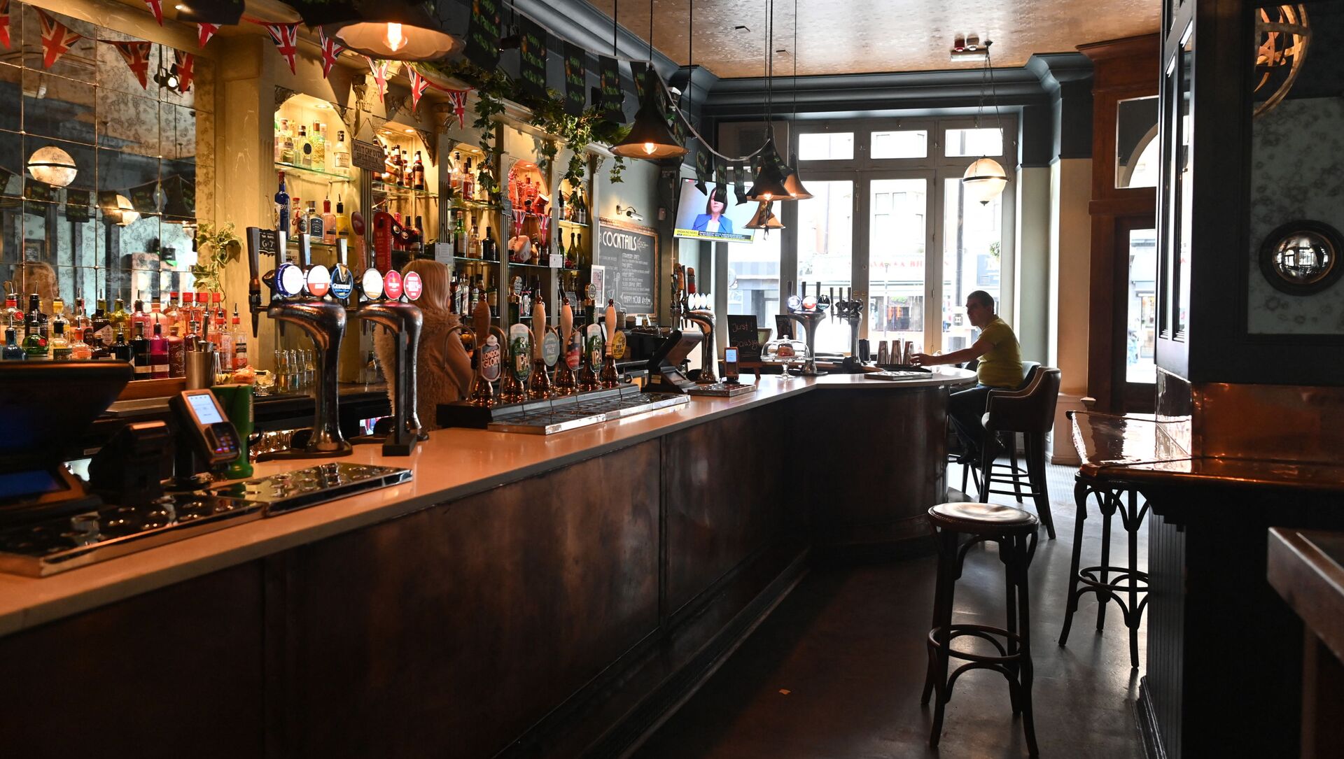 A single customer sits at the bar in a near-empty pub in central London on March 17, 2020 after the UK government announced stringent social distancing advice including avoiding pubs and restaurants as a measure to kerb the spread of novel coronavirus COVID-19 - Sputnik International, 1920, 24.02.2021