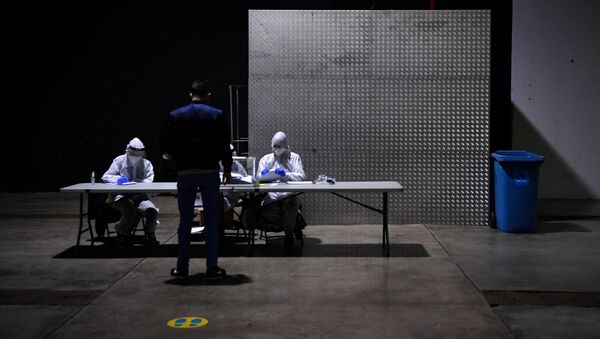 Officials wear Personal Protective Equipment (PPE) as a person casts his ballot during the voting period assigned for those infected with COVID-19 at a polling station in L'Hospitalet de Llobregat during regional elections in Catalonia on February 14, 2021.  - Sputnik International